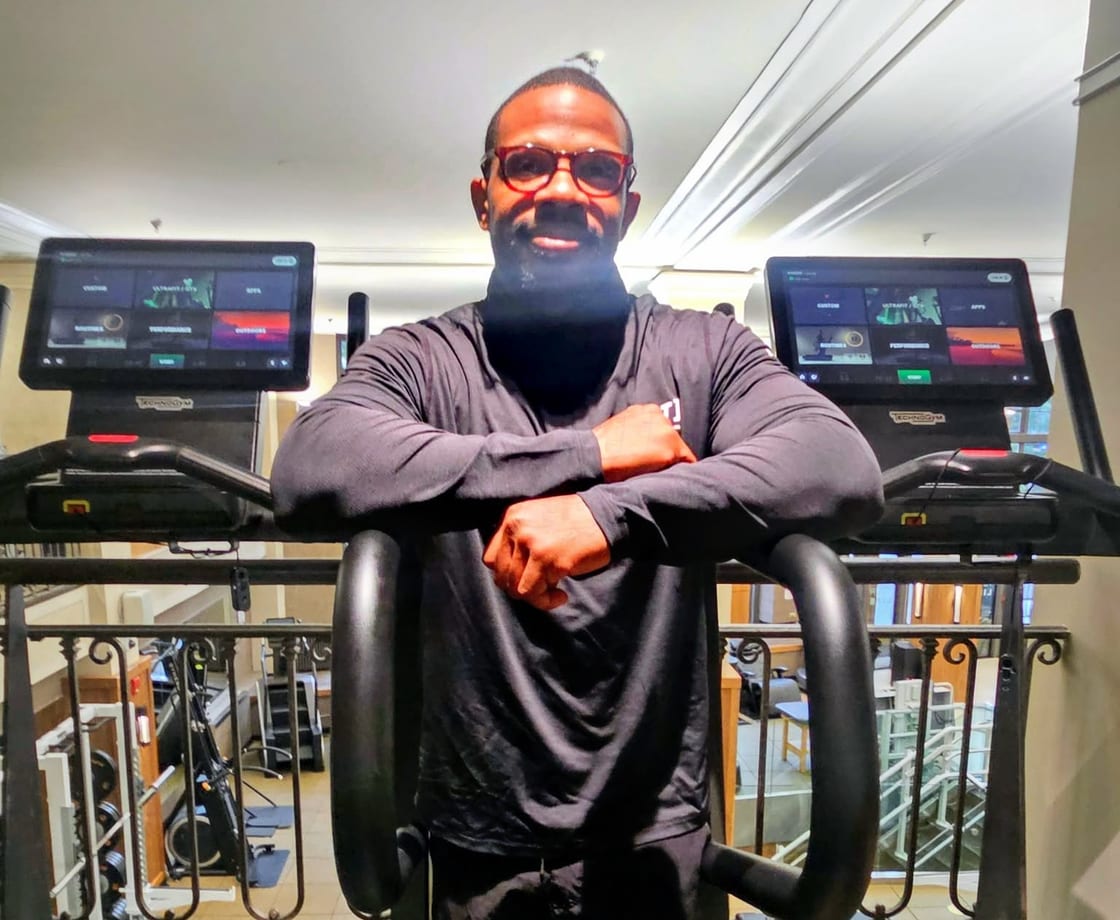 Junard today, smiling and leaning on a treadmill in the gym